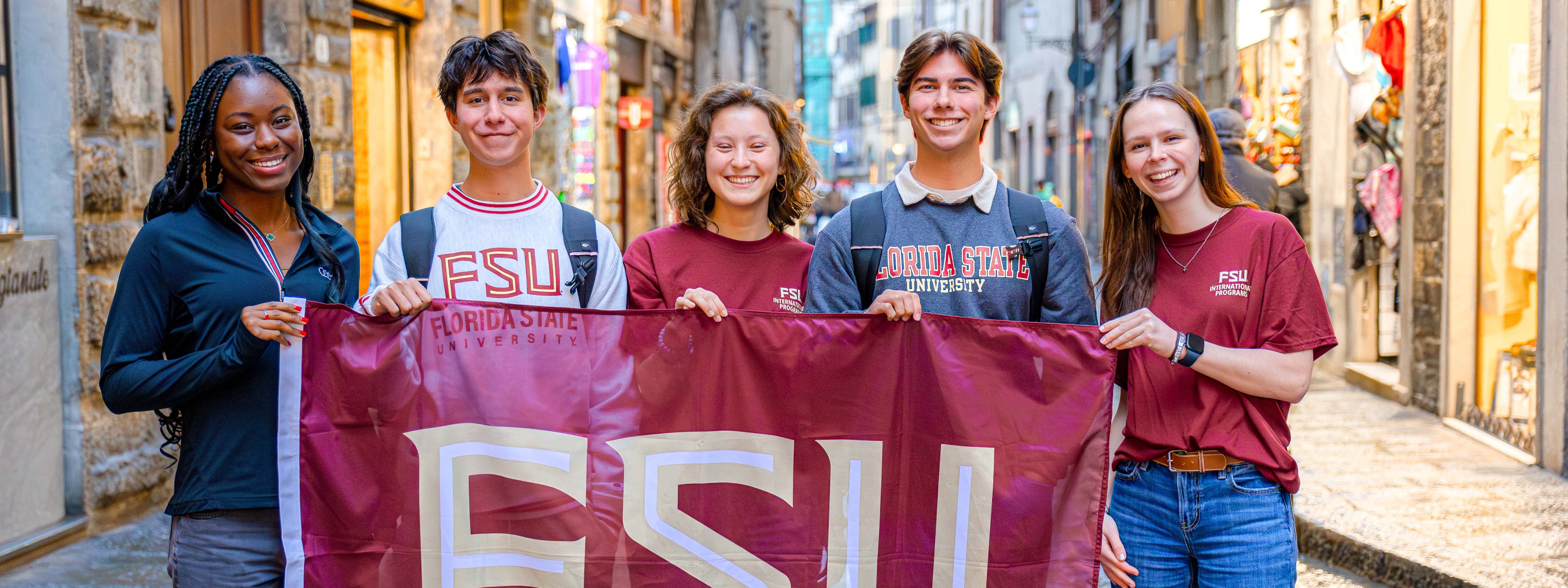 First Year Abroad students holding an FSU flag in the streets of Florence.