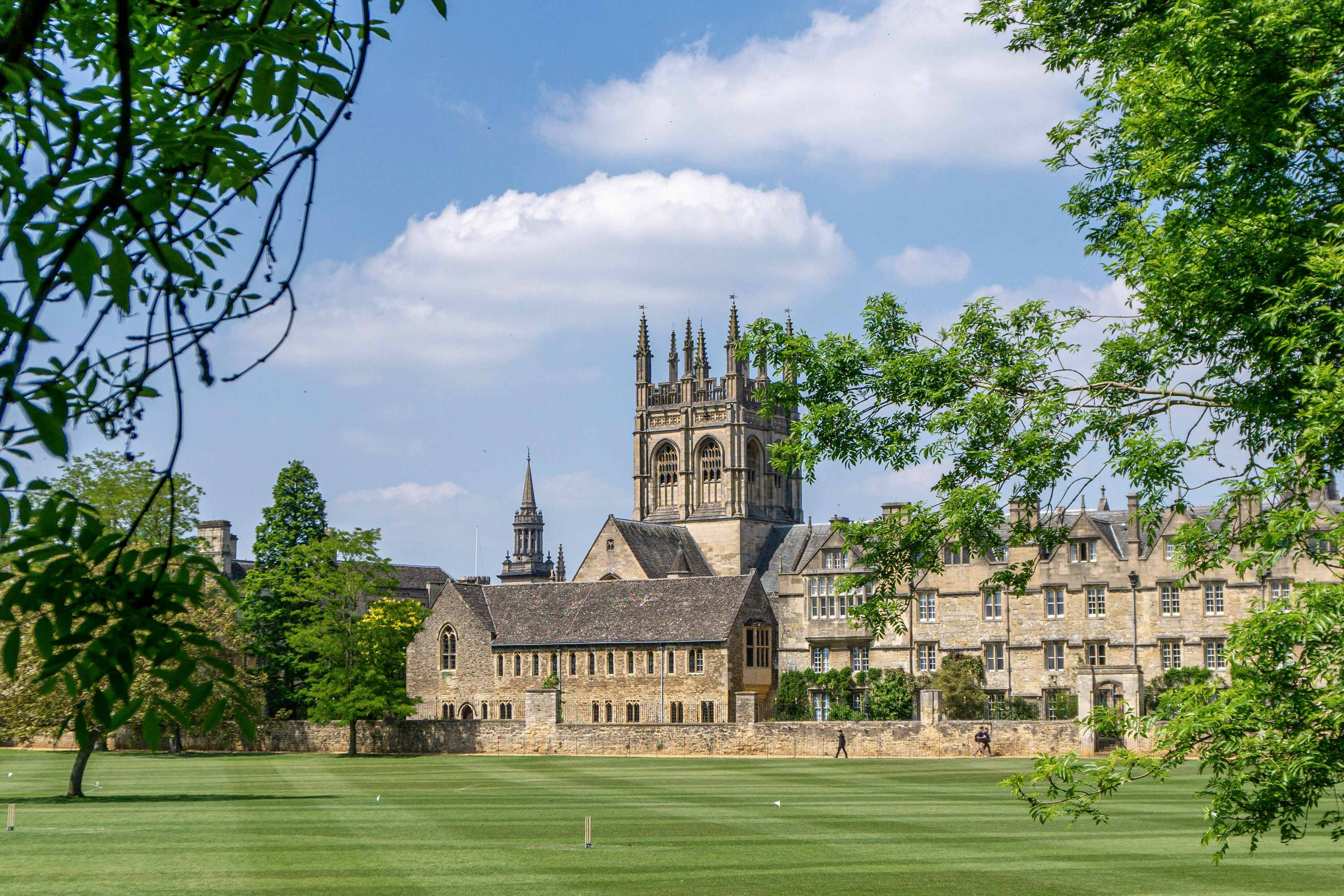 A view of Oxford with foliage and lawn in the foreground.